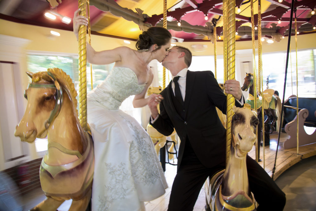 photographer bride and groom kissing on merry go round carousel