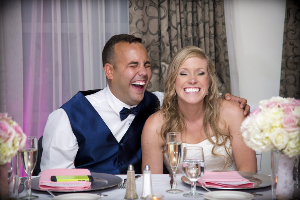 photograper bride and groom laughing at table during ceremony